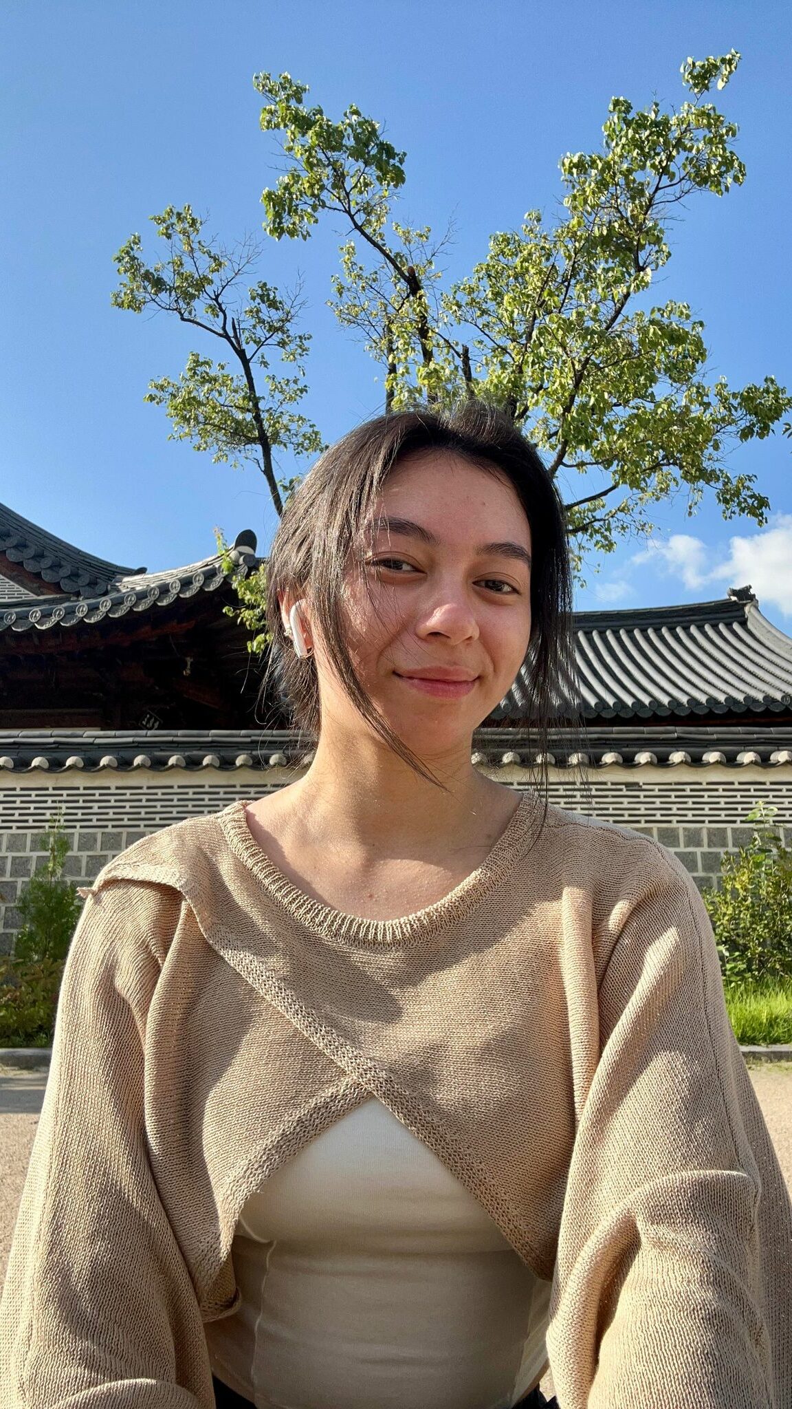 young female sitting outside smiling for the camera in a Korean historical palace background